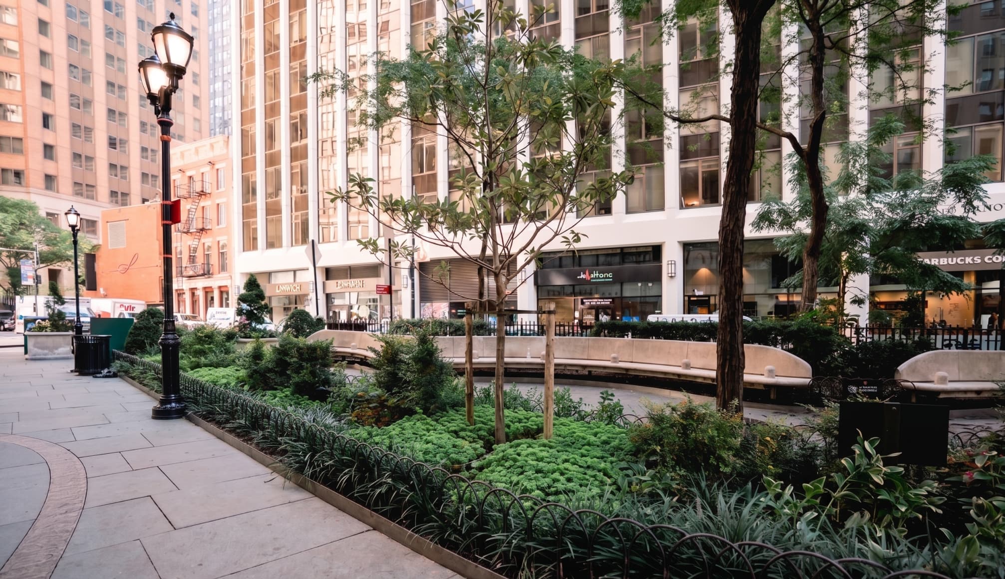 A leafy public garden surrounded by New York City buildings